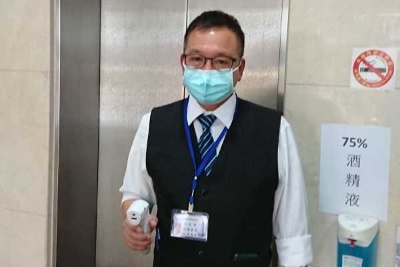 筆者が入居するビルの1階ロビーの様子。右側には75%アルコール消毒液(非接触型)が置かれ、管理人が非接触型の体温計で体温をチェックする。37.5度未満と確認され、 かつマスク着用と両手のアルコール消毒をしたらビルに入れる(筆者撮影)